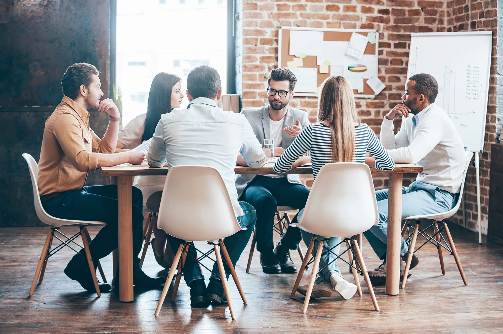 A diverse team gathered around a table in a discussion, illustrating a workplace culture of health and learning